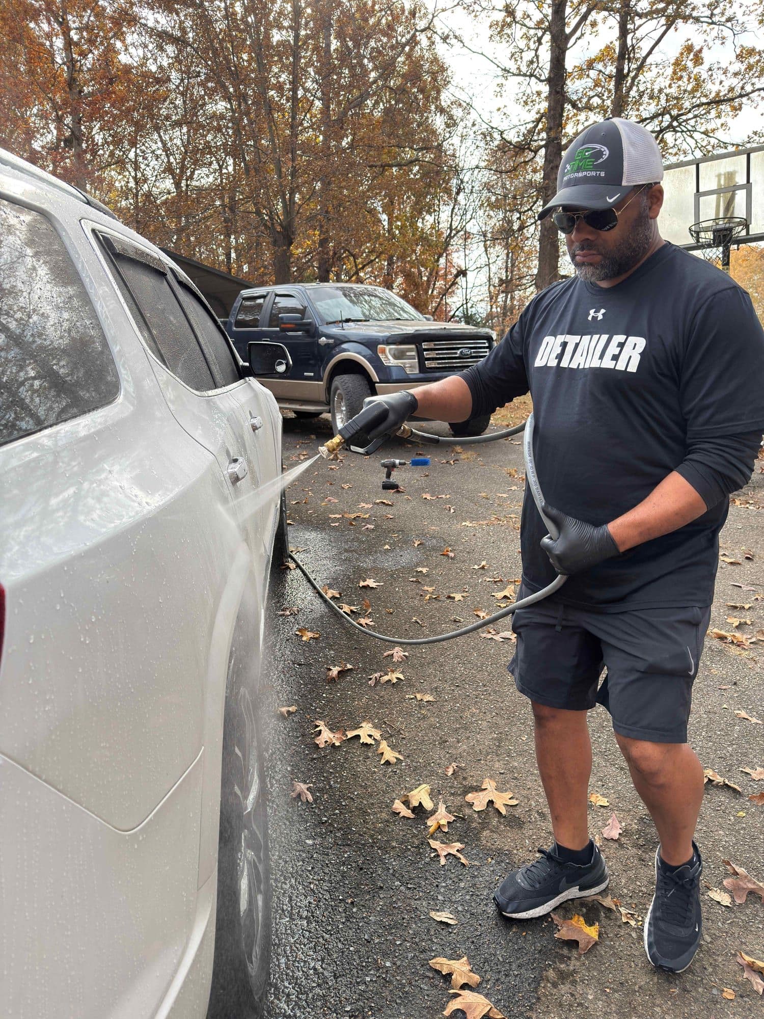 Gavin Brooks pressure-washing a vehicle in a DETAILER shirt