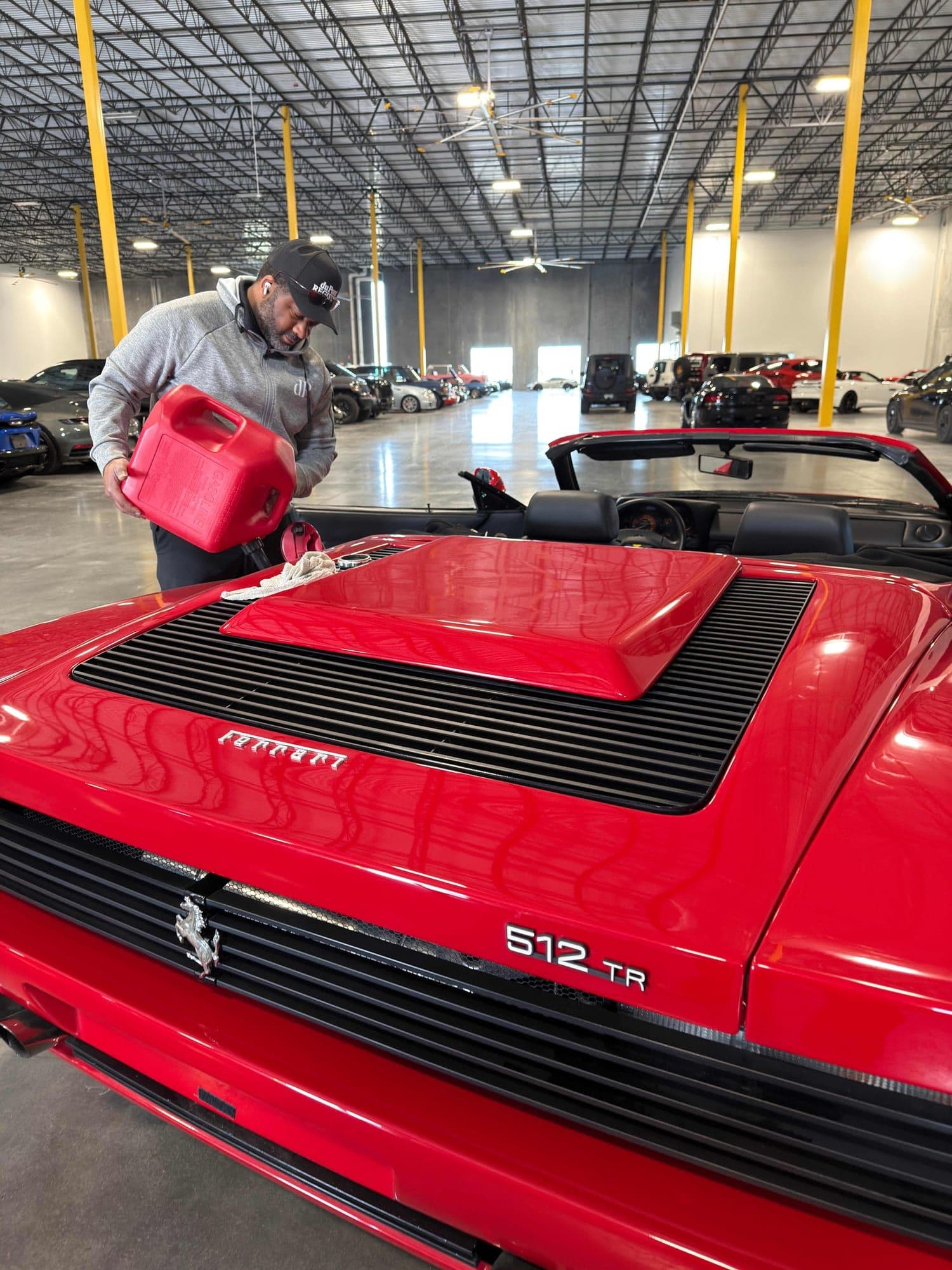 Gavin Brooks servicing a red Ferrari 512 TR in the warehouse