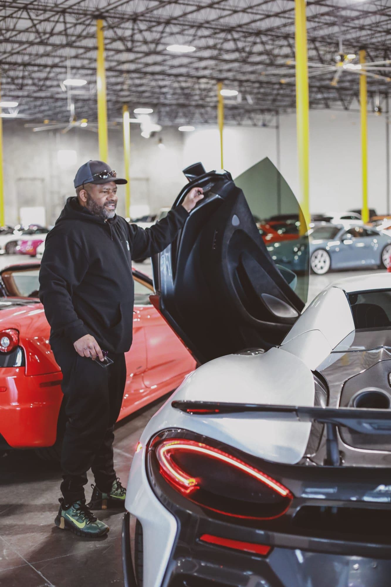 Gavin Brooks opening the dihedral door of a McLaren among rows of exotics